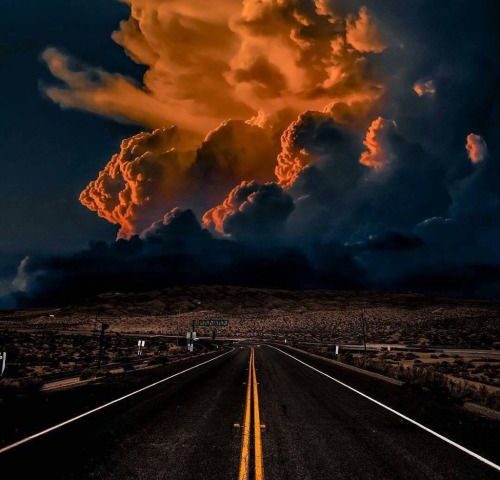 Empty road toward dramatic glowing storm clouds