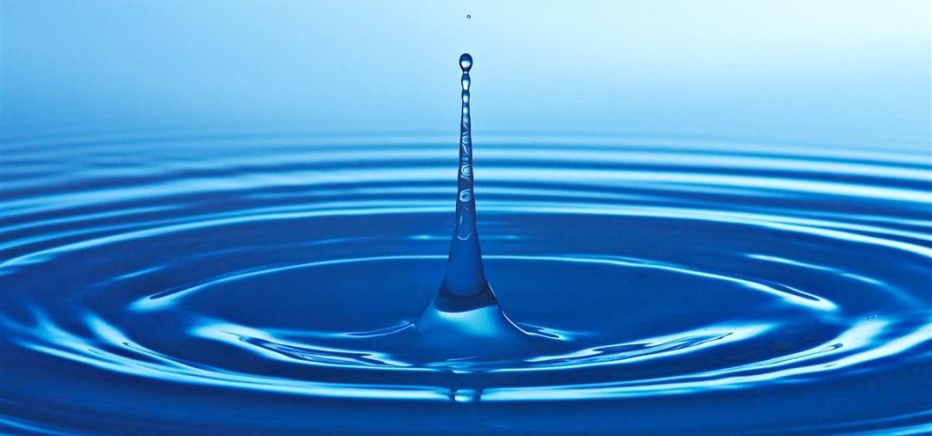 Blue water droplet creating concentric ripples